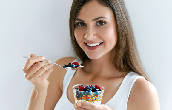 Since 1919, we have believed in the value contributed to the everyday diet by dairy products woman eating natural yogurt with fruits